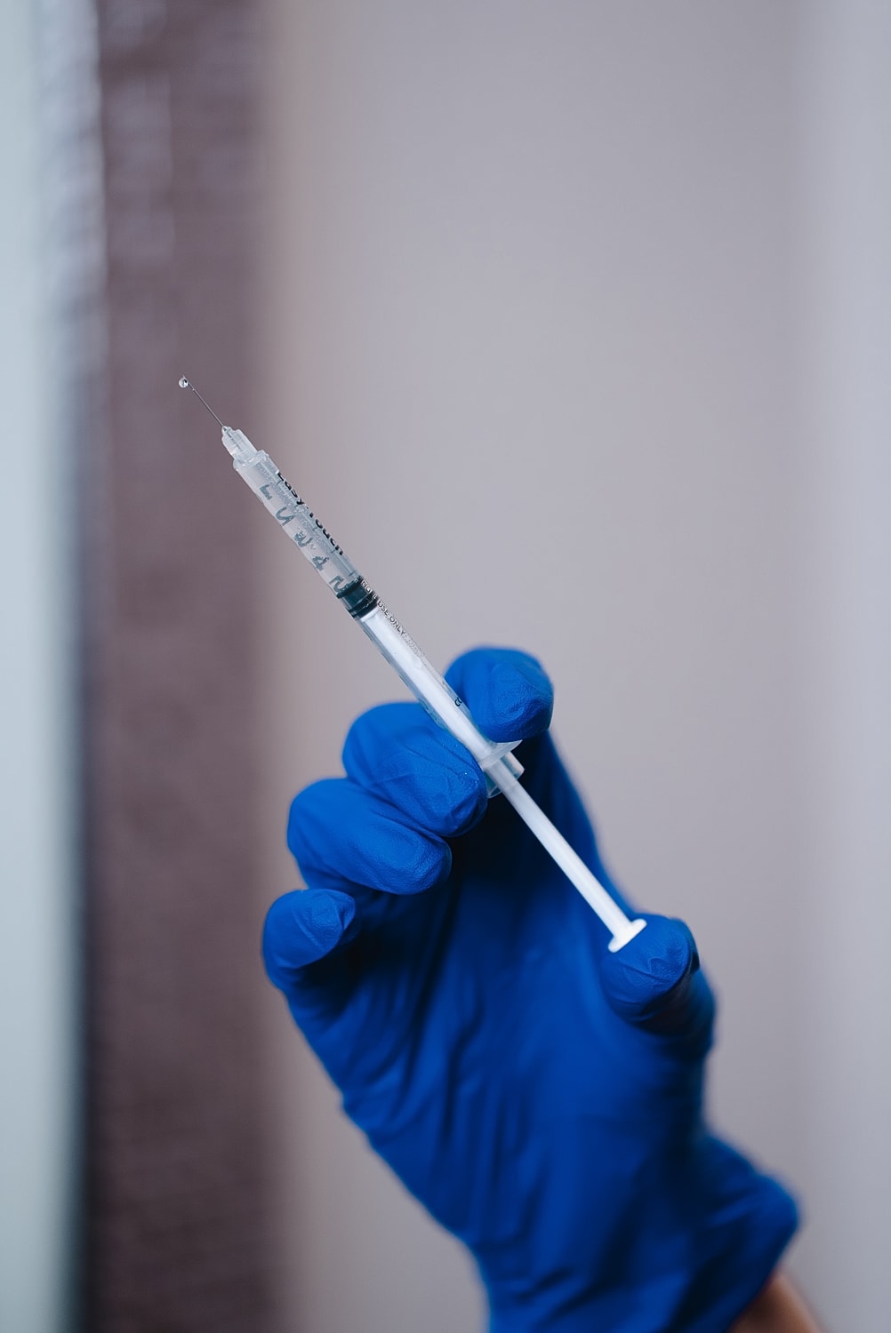 Gloved hand holding a syringe with liquid.