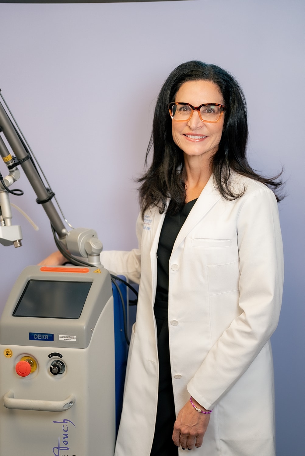 Medical professional beside laser treatment equipment.