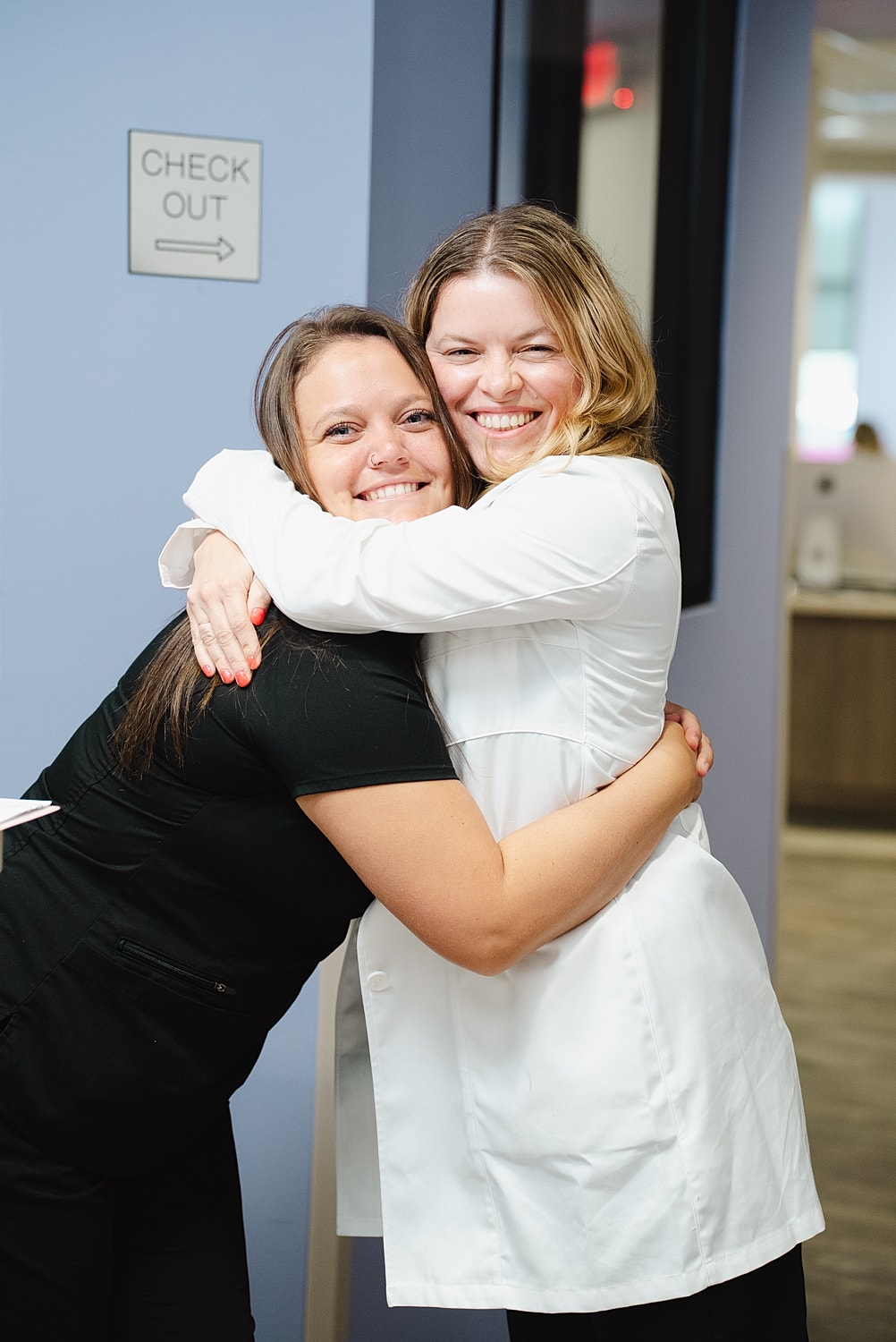 Two women hugging in an office setting.