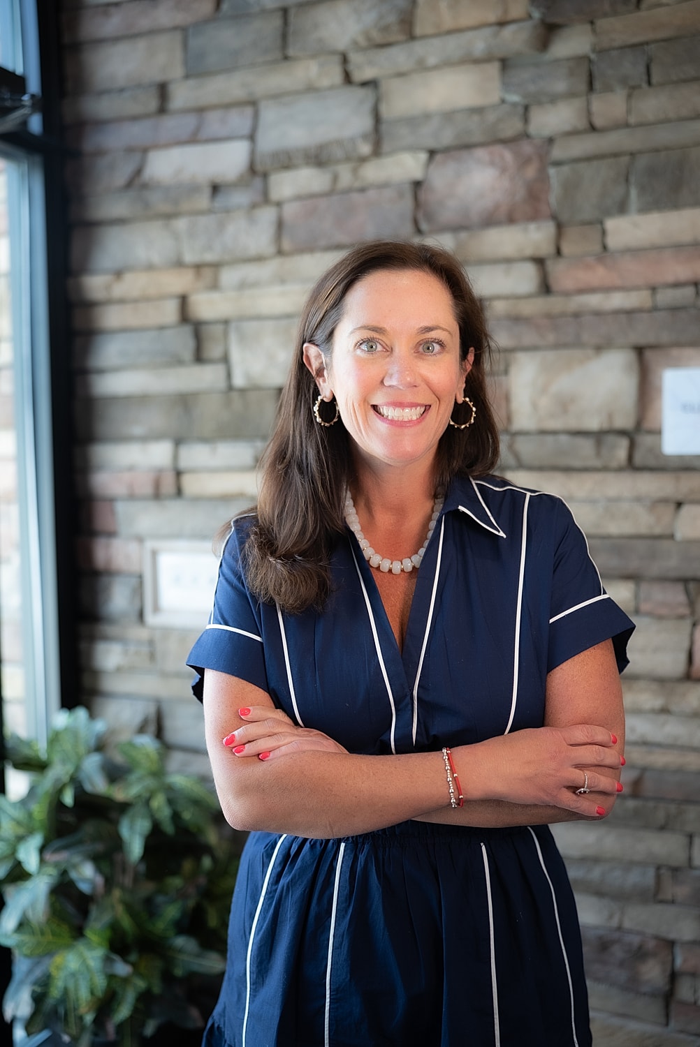 Smiling woman in front of stone wall.