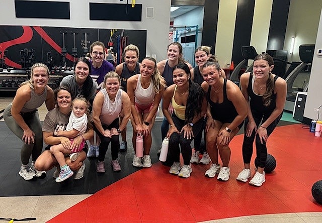 Group of women posing in a gym.