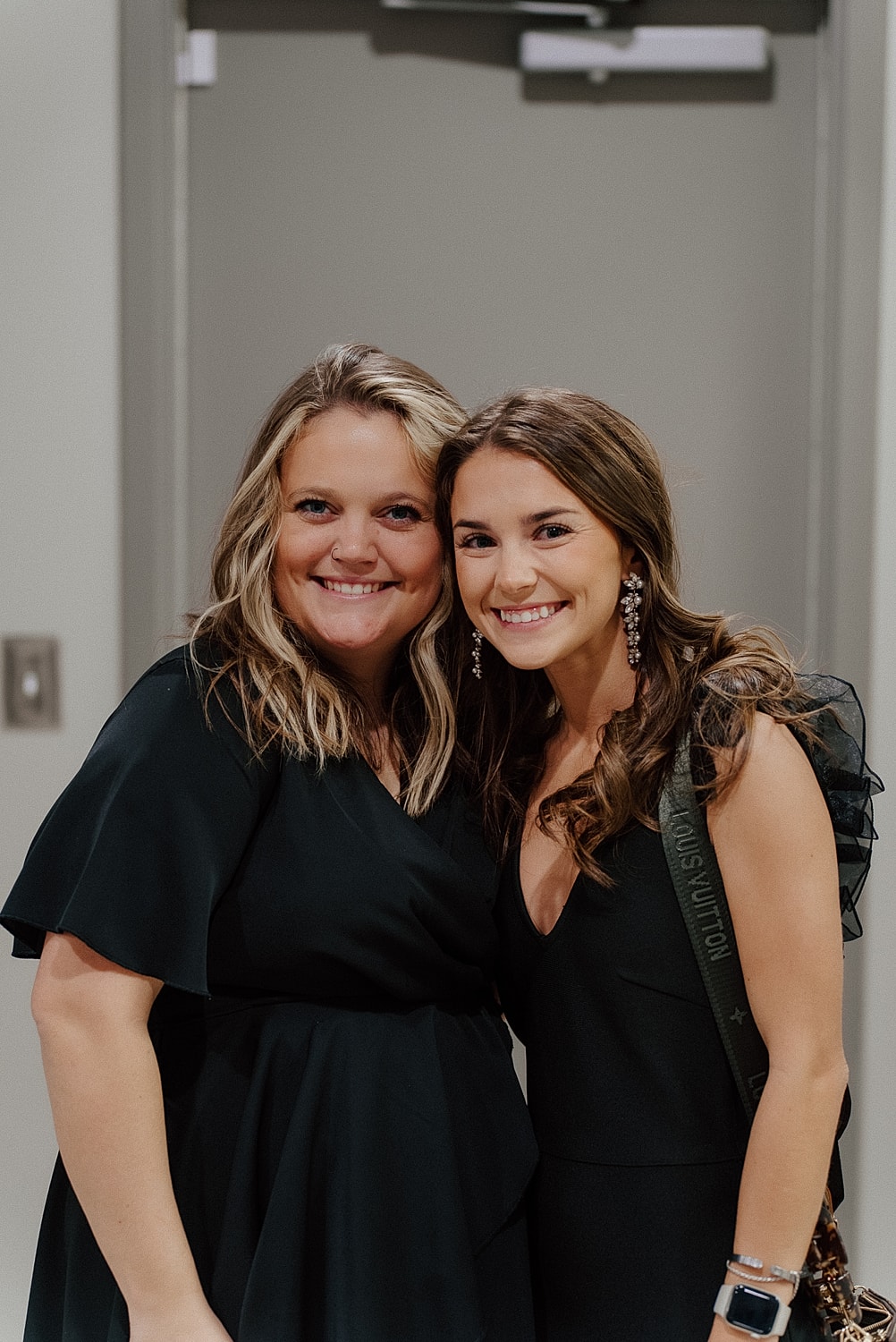 Two women smiling in elegant black dresses.