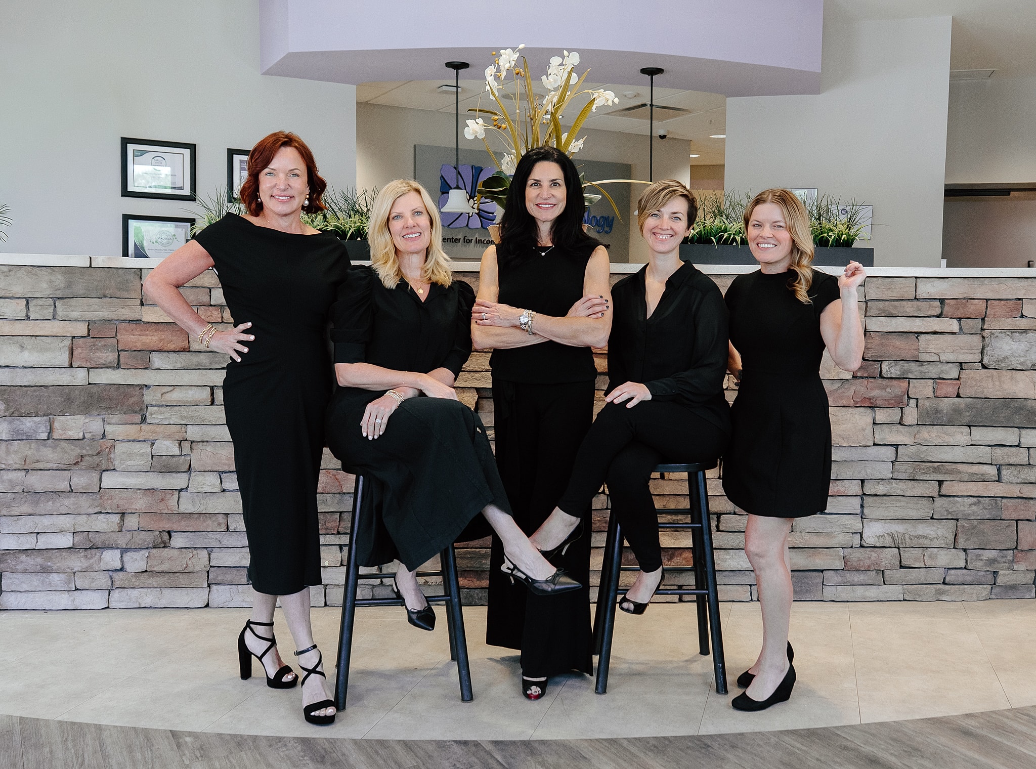 Five women posing in a professional setting.