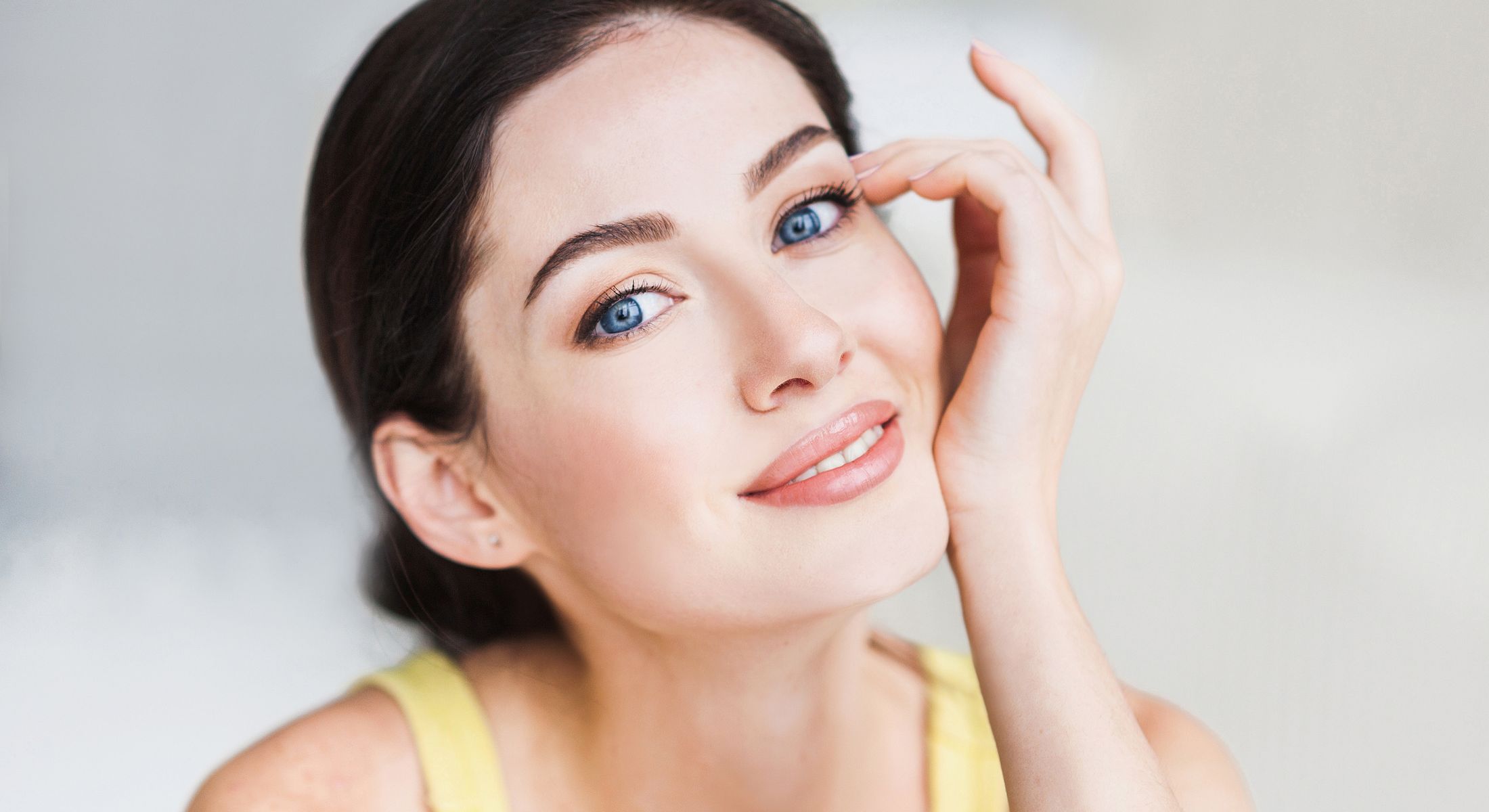 Woman applying skincare in bright bathroom setting.
