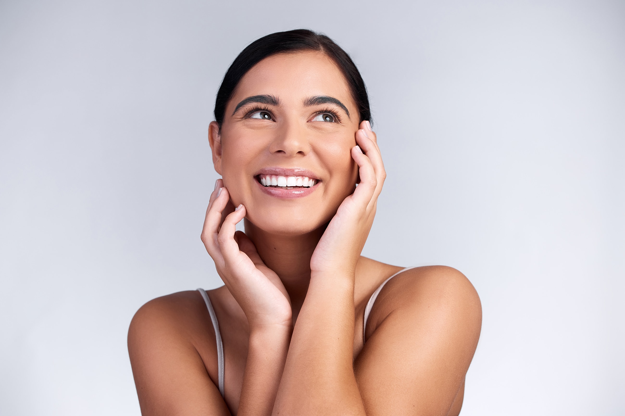 Smiling woman with natural makeup, light background.